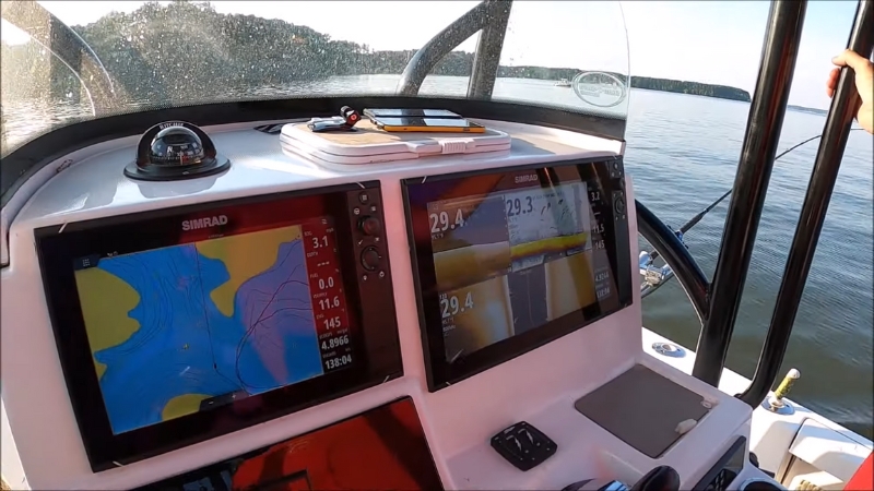Fish finder display showing sonar readings and depth information on a boat dashboard in calm water