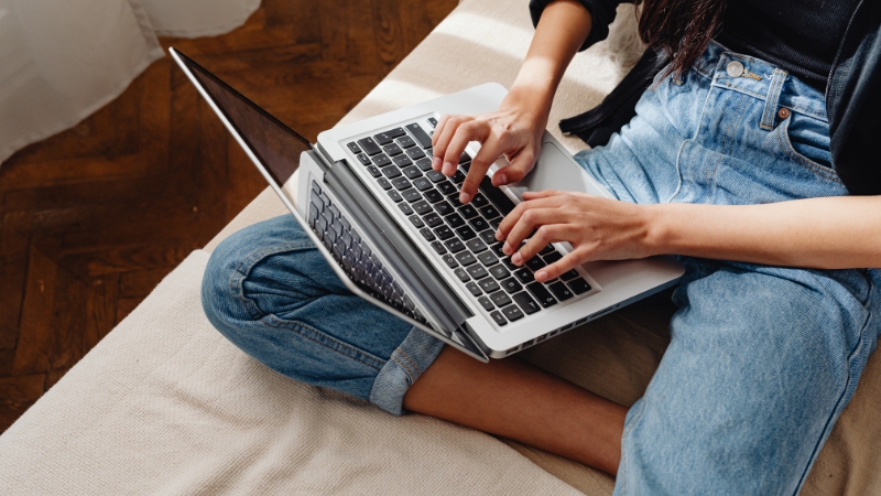 Woman typing on a laptop, creating digital content to support marketing efforts for an outdoor brand