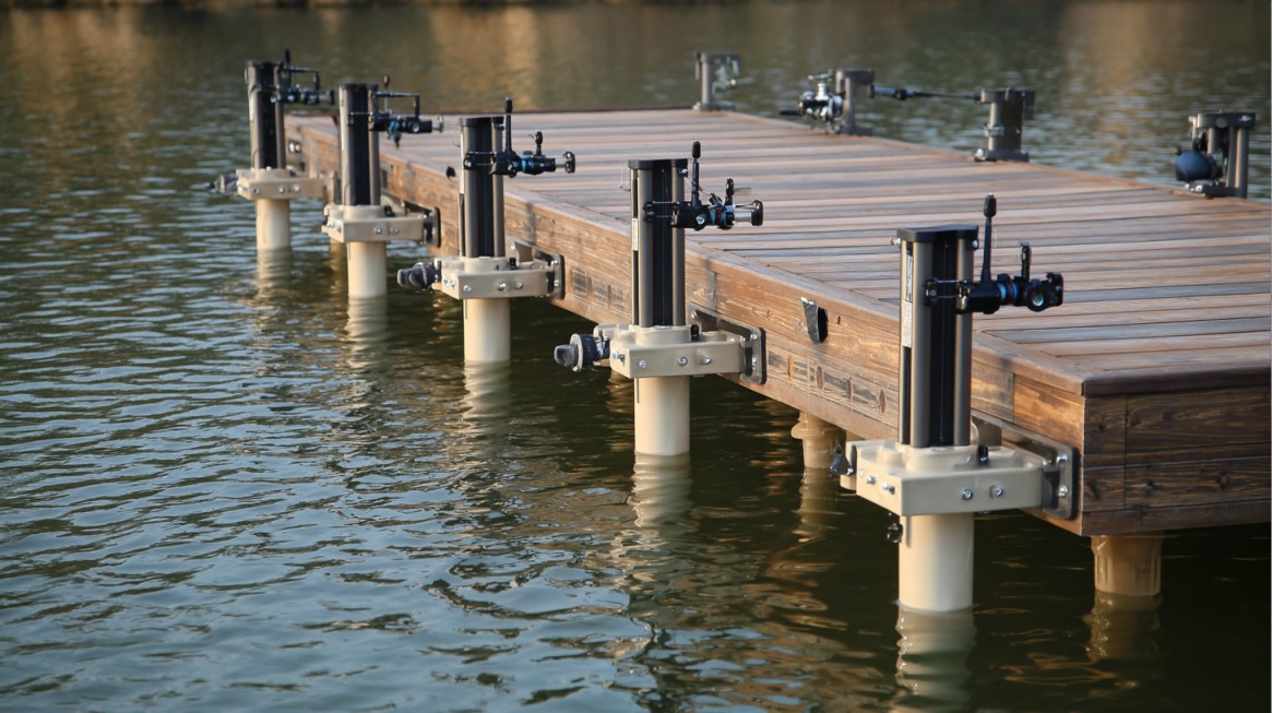 Sturdy fishing rod holders mounted along the edge of a wooden dock extending over calm water