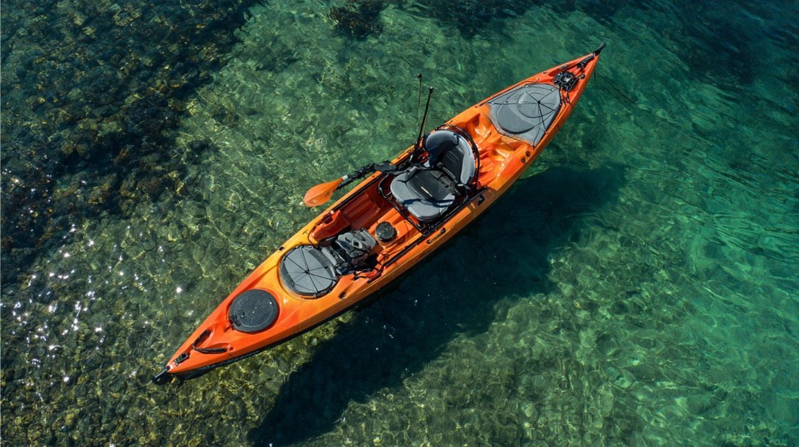 Aerial view of an orange fishing kayak floating over clear, shallow water