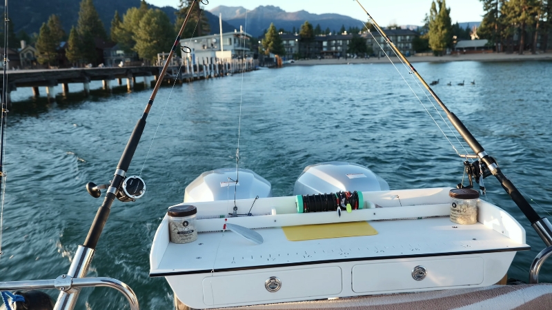 Two rods rest on a small boat setup ready for fishing in Lake Tahoe near a quiet marina