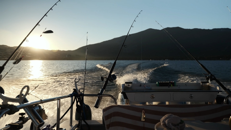 Fishing rods line the back of a boat moving across Lake Tahoe at sunrise