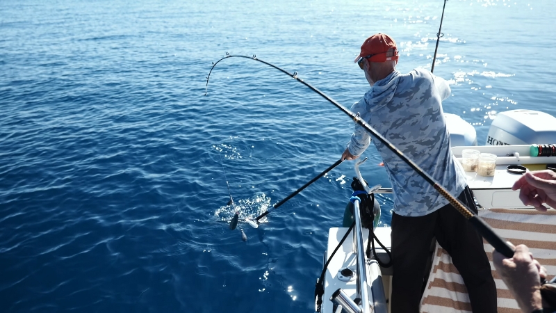 An angler on a boat reaches with a net toward a fish near the surface of Lake Tahoe