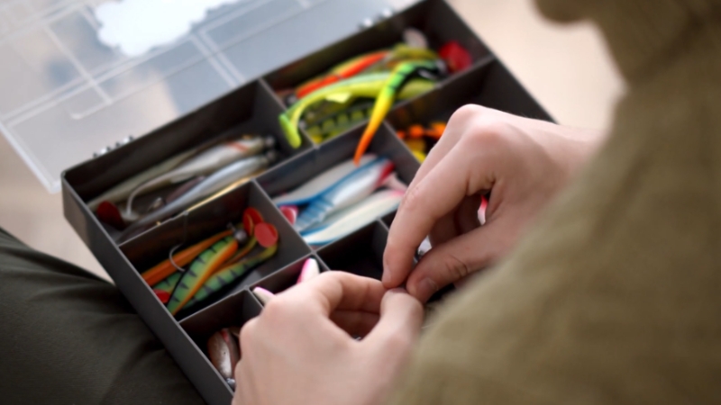 An angler sorts colorful lures in a tackle box before setting up a rig