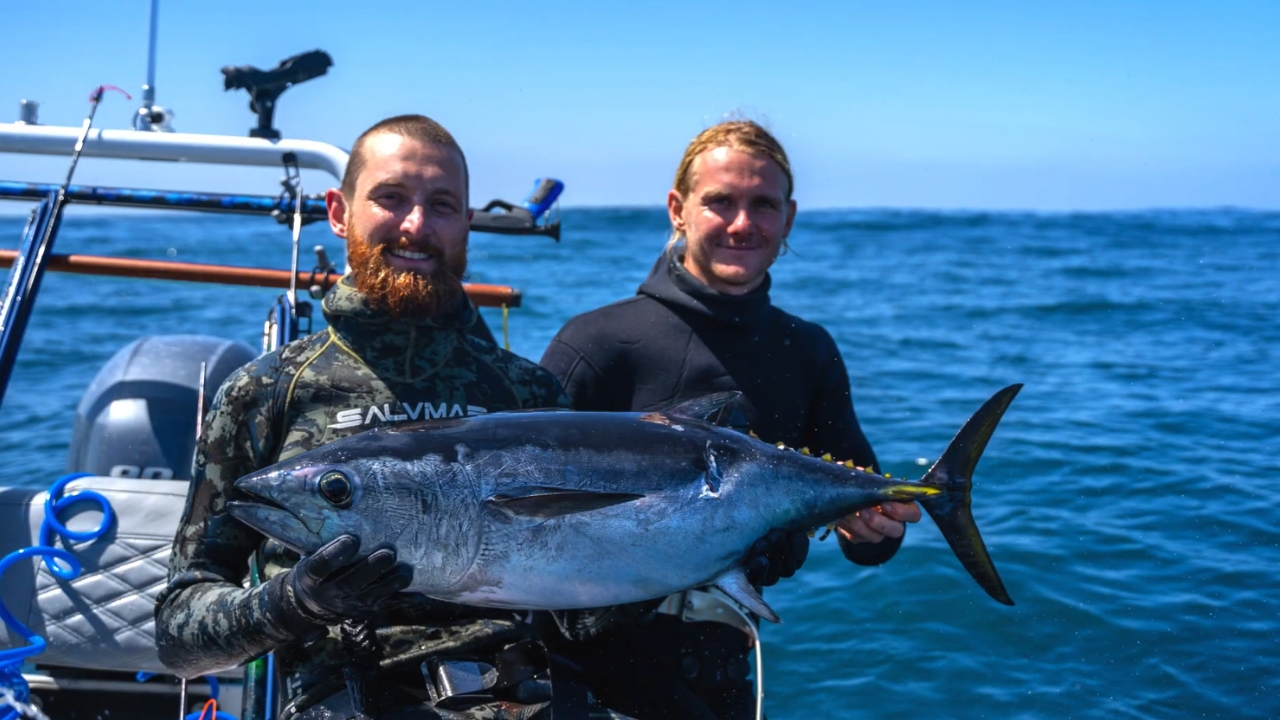 Two anglers hold a southern bluefin tuna on a small boat at sea