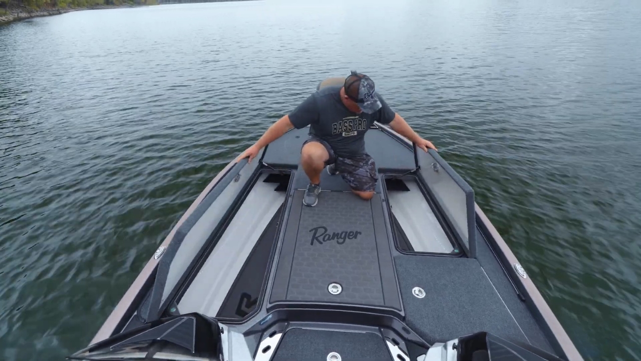 An angler checks open compartments on a bass boat on a calm lake