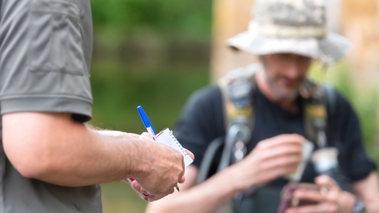A guide writes notes beside an angler with a fish
